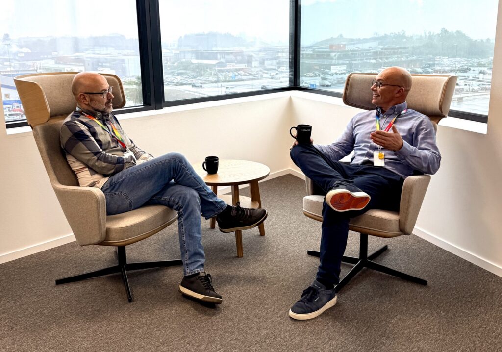 Fra venstre: Christer Olerud, LBU & Market Manager, og Jørgen Johannessen, Regional Manager, i Hitachi sitter i samtale i Midtbygget med utsikten i bakgrunnen.